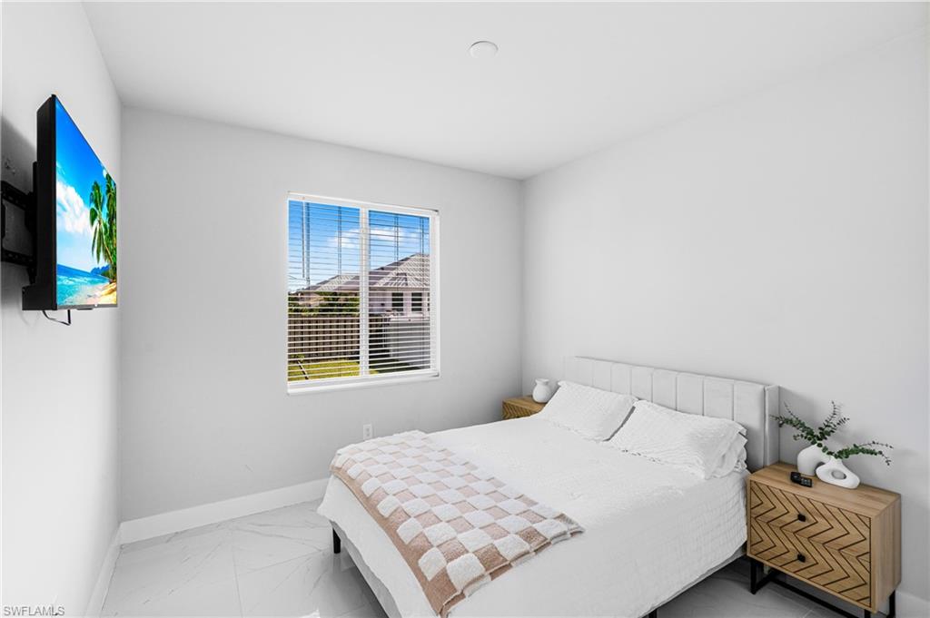 White paneled headboard, built-in window with horizontal blinds, and tile flooring