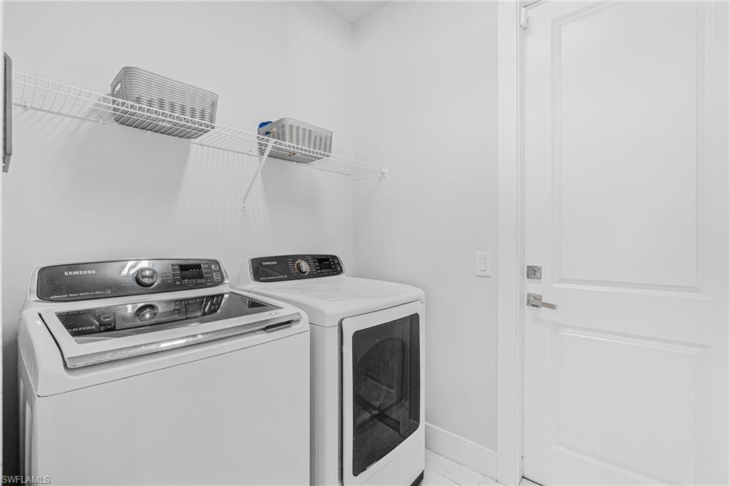 Dedicated laundry area featuring a washer, dryer, wire shelving, and a paneled door with brushed nickel hardware