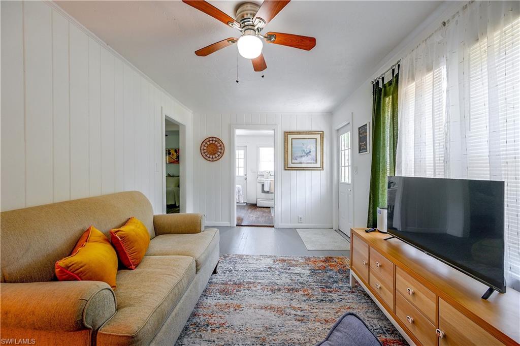 White paneled walls, ceiling fan with wood-finish blades, and wood-finish flooring