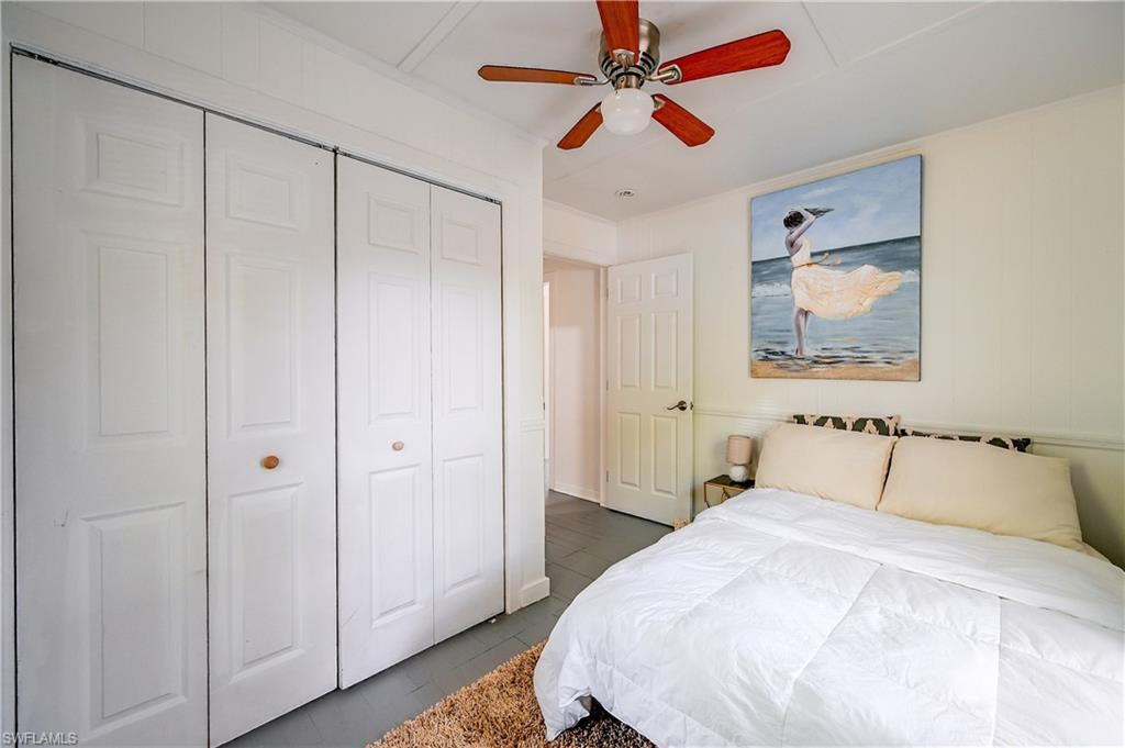 White paneled bi-fold closet doors, ceiling fan with light fixture, and tile flooring