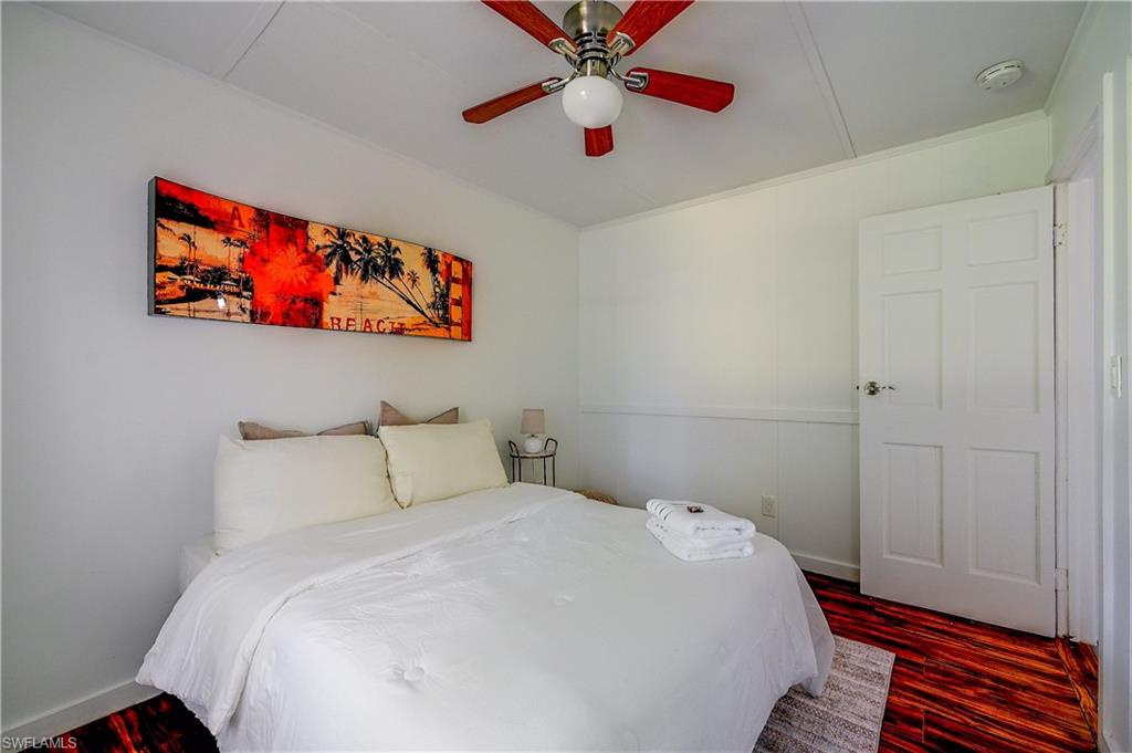 Wood-finish flooring, white panel walls, and a ceiling-mounted fan fixture