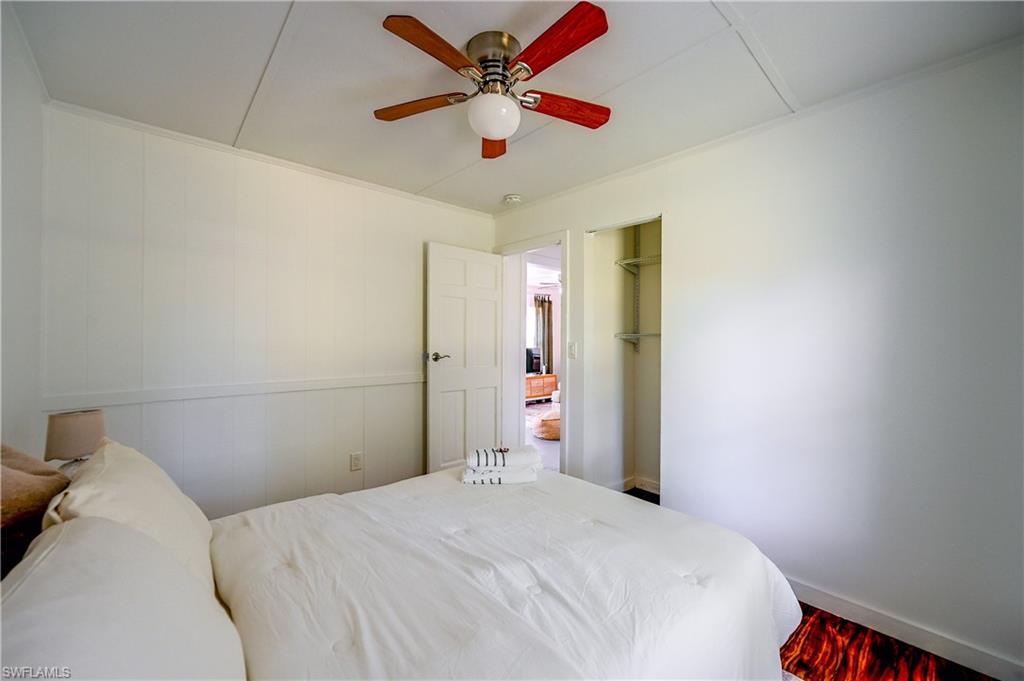 White paneled walls and wainscoting with a ceiling fan overhead