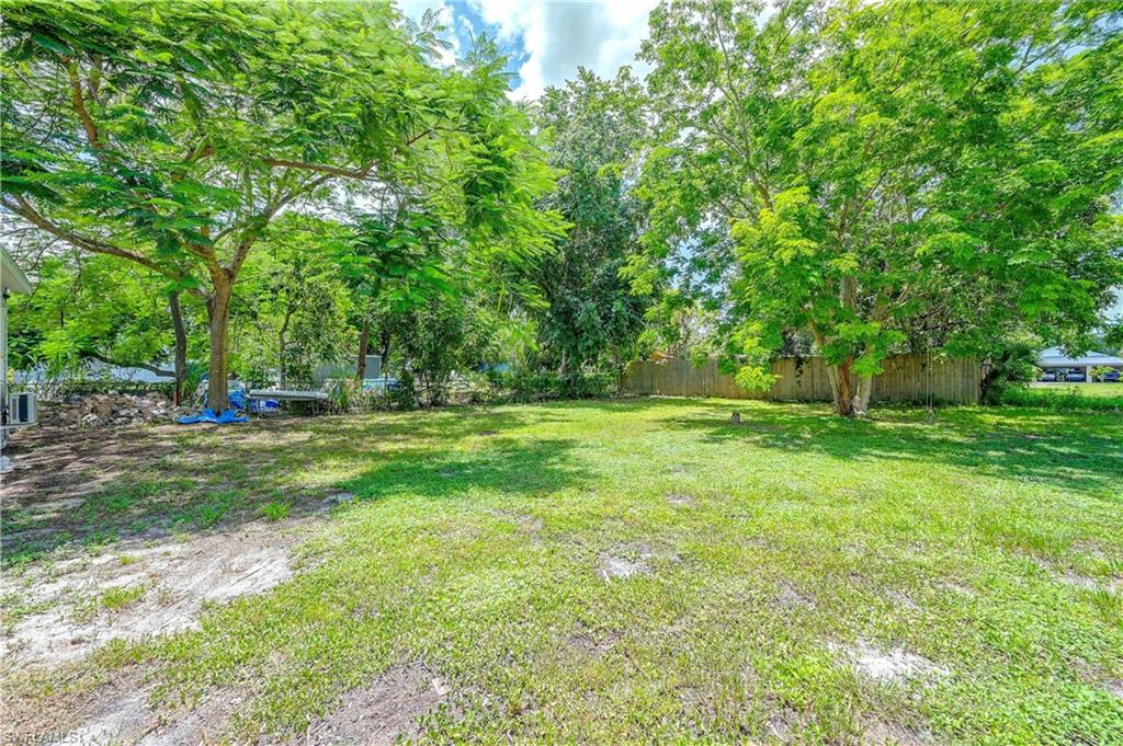 Expansive lawn area with mature trees and partial fencing