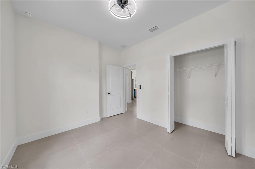 Recessed lighting, light tile flooring, white walls, white trim, and a bi-fold closet door