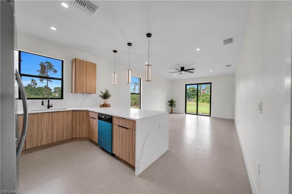 Contemporary kitchen featuring light wood-finish cabinetry, quartz countertops, a center island with pendant lighting, and an integrated dishwasher