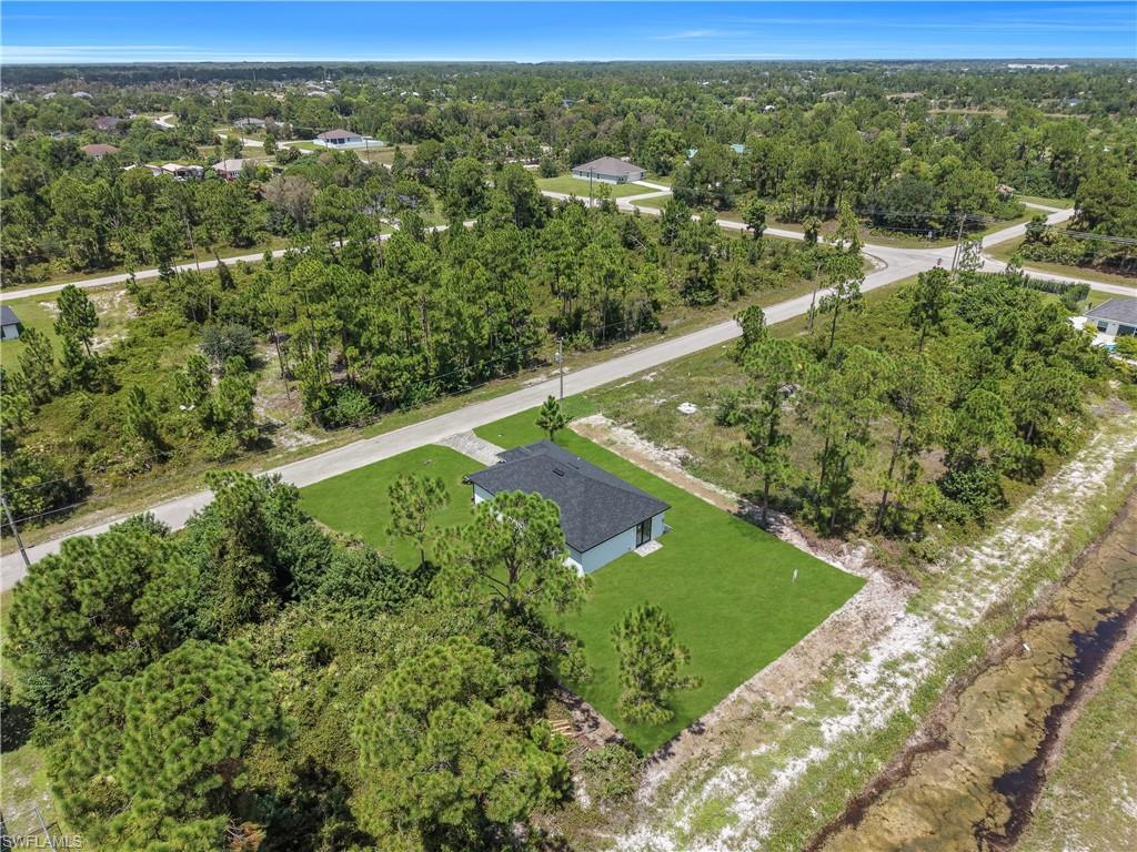 New construction residence with dark shingle roofing, light-colored exterior siding, and a well-maintained lawn