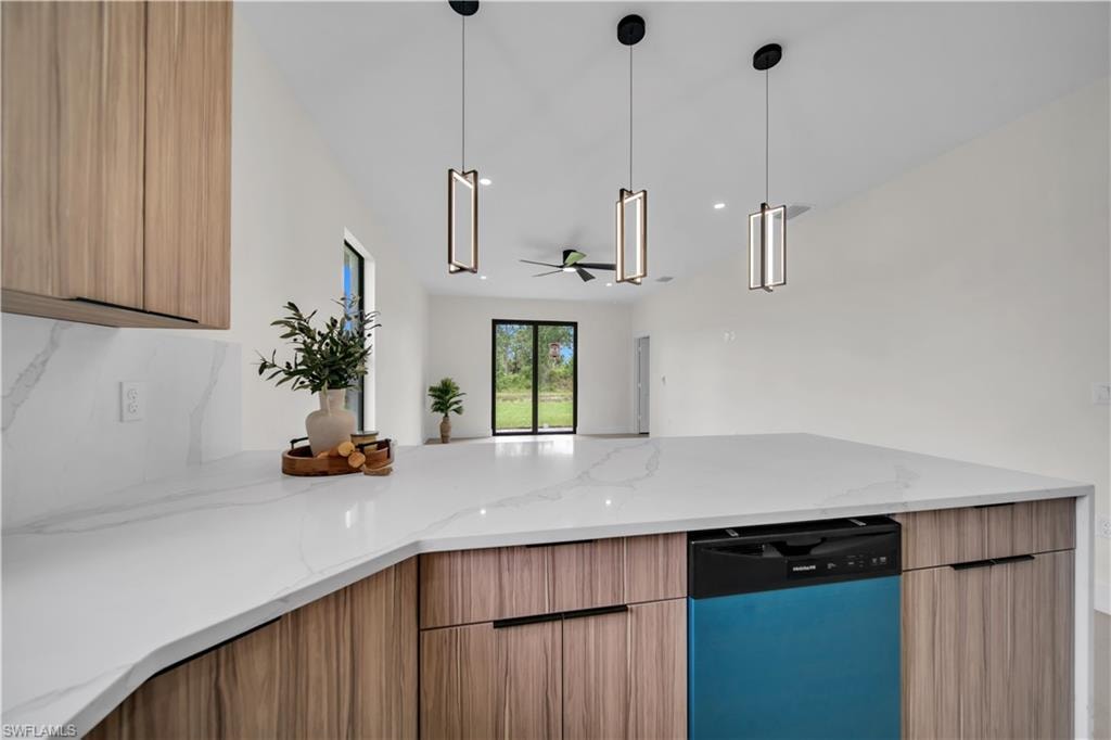 Spacious kitchen island with white countertop, integrated dishwasher, wood-finish cabinetry, and contemporary pendant lighting