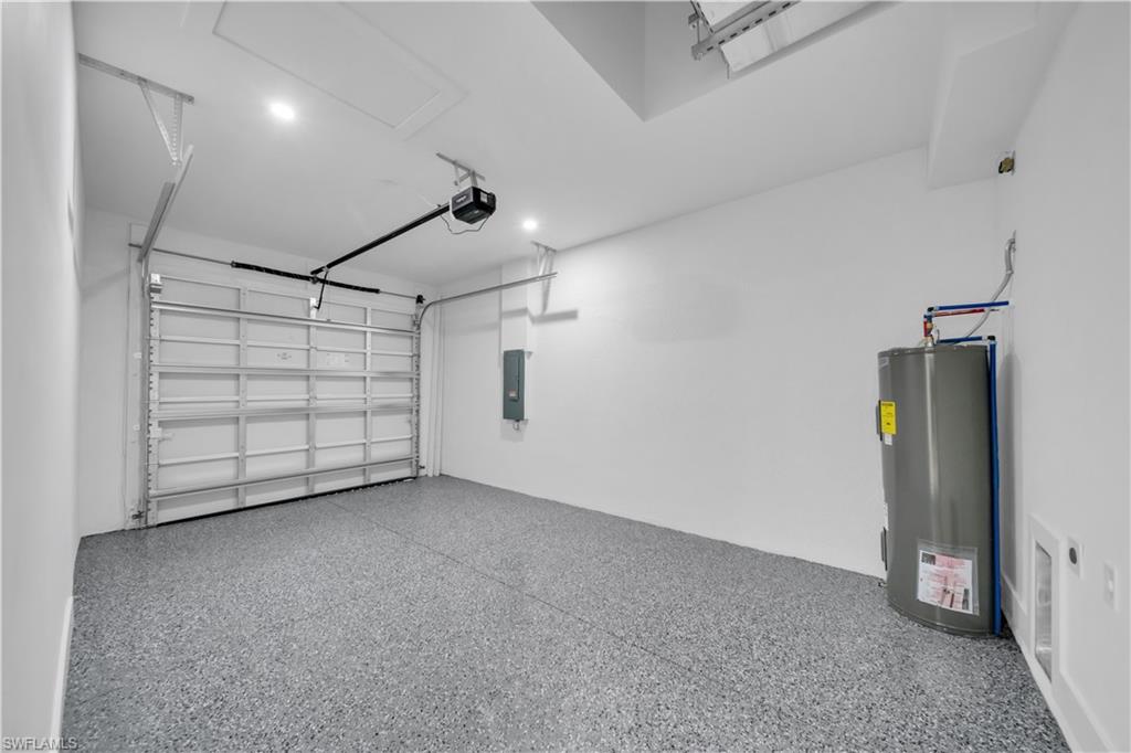 Spacious garage featuring a sectional garage door, epoxy flooring, overhead lighting, and a water heater