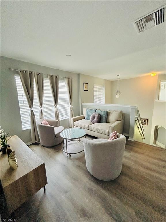 Wood-finish flooring throughout, multiple windows with blinds, and an open balcony overlooking a lower level