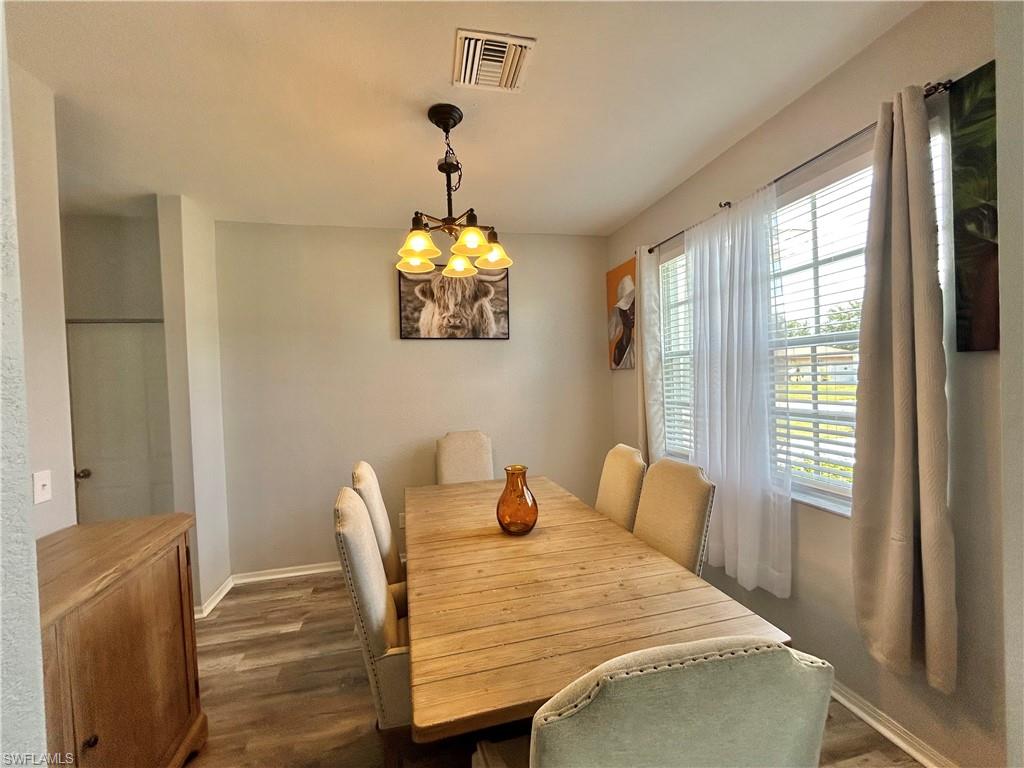 Dining area featuring wood-finish flooring, a multi-pane window with blinds, and a built-in light fixture