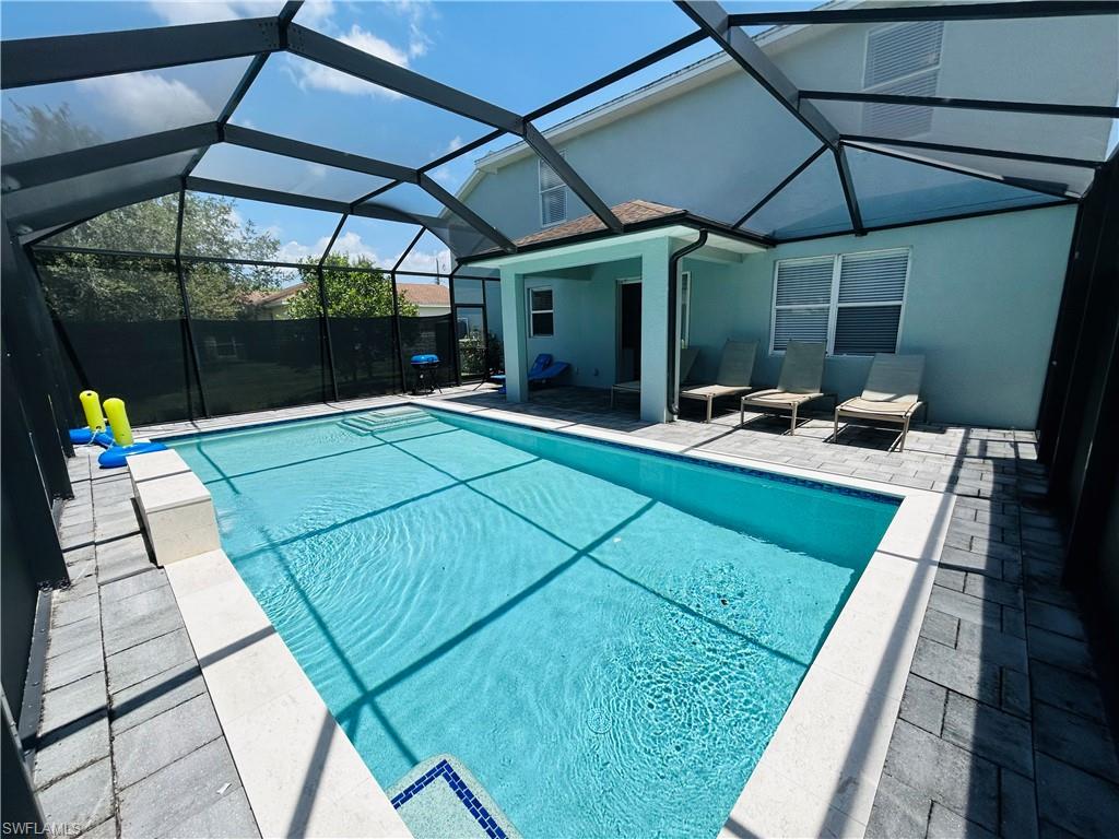 Screen-enclosed swimming pool with a paved deck