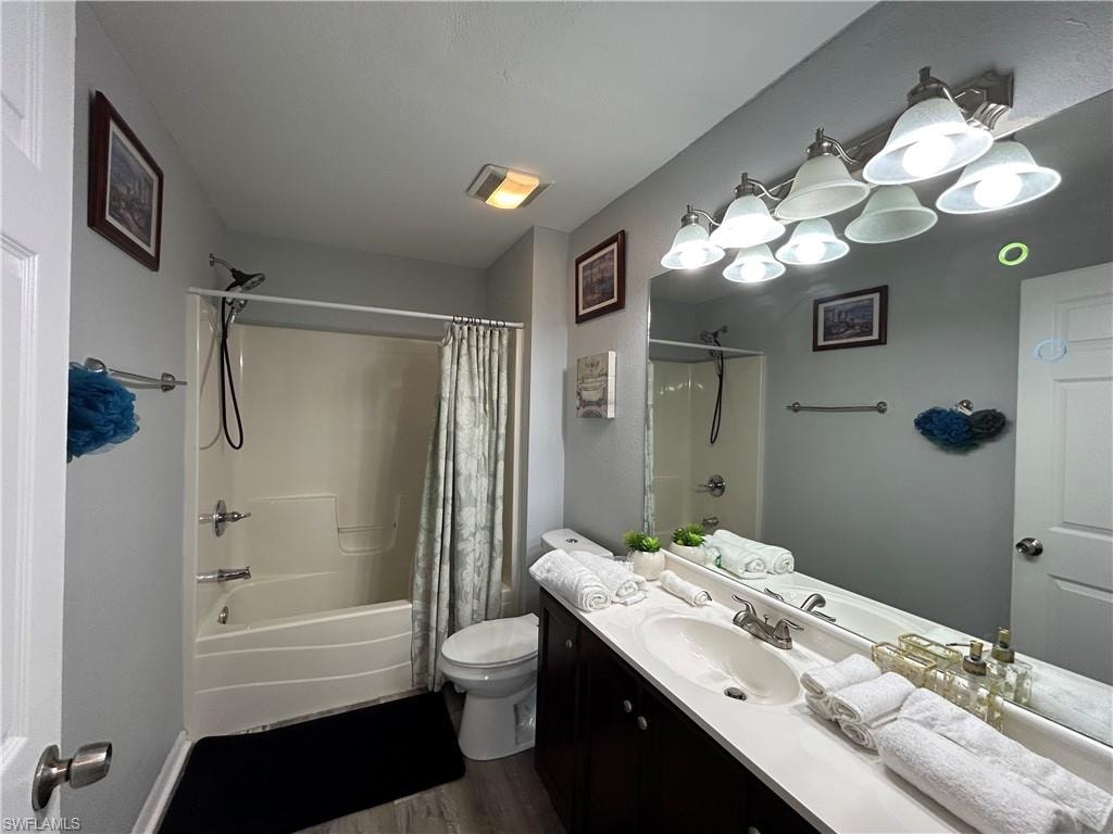 Vanity with single basin sink, expansive mirror, and a wall-mounted light fixture