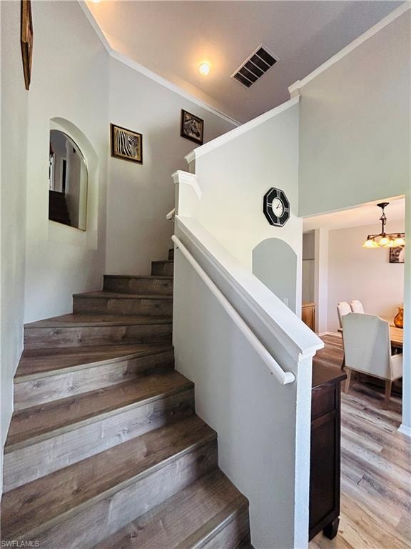 Staircase featuring wood-finish treads and risers, white painted handrail, and arched wall opening