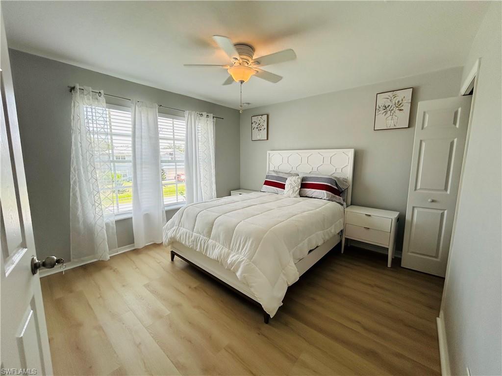 Wood-finish flooring, ceiling fan with integrated lighting, two windows with blinds, and a built-in closet
