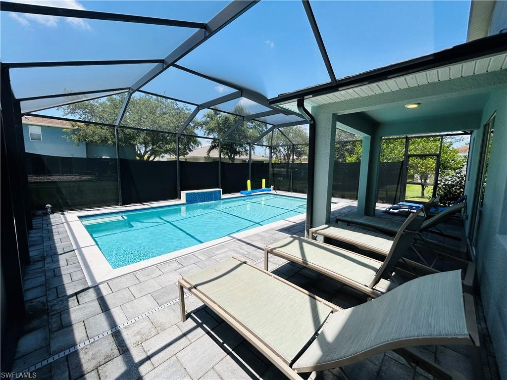 Screened-in pool enclosure featuring a rectangular pool with integrated spa and a tiled waterfall accent