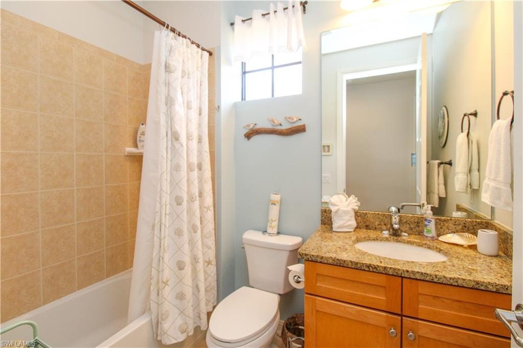 Full bathroom with vanity, toilet, and shower / bathtub combination with curtain