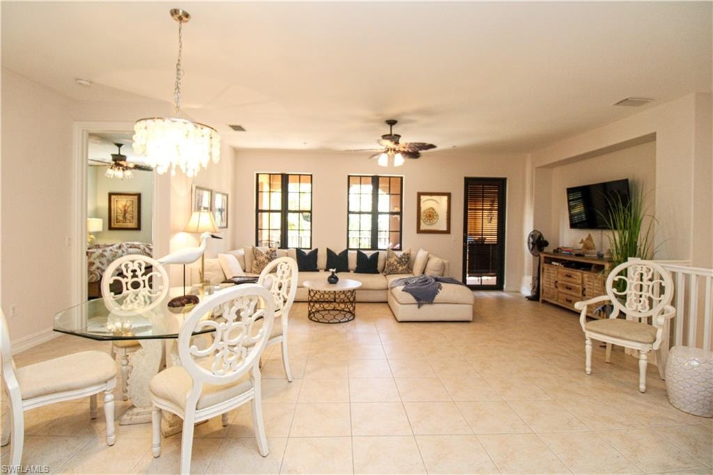 Dining area featuring light tile patterned flooring and ceiling fan with notable chandelier