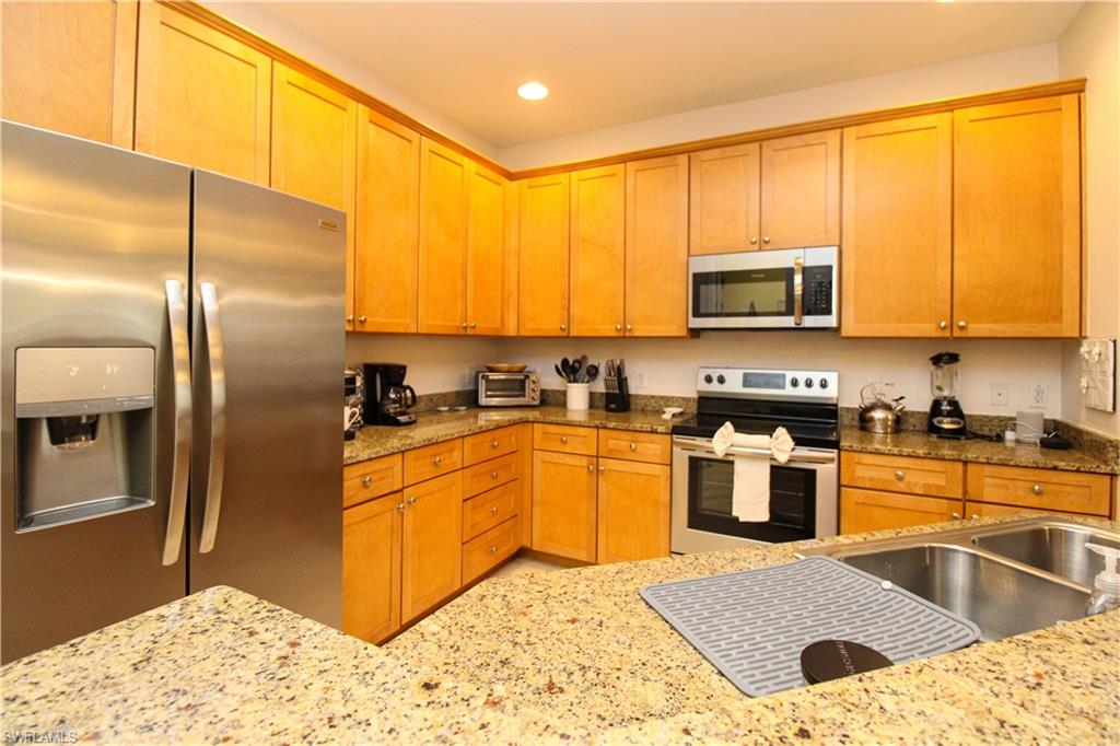 Kitchen with light stone countertops and appliances with stainless steel finishes