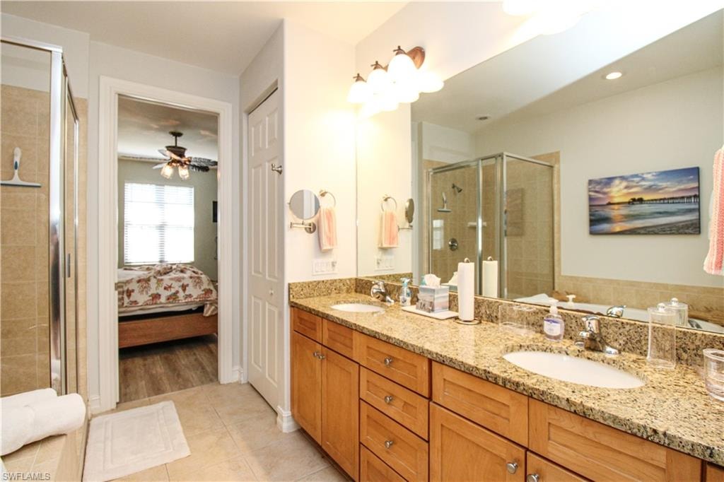 Bathroom with vanity, ceiling fan, a shower with shower door, and tile patterned floors