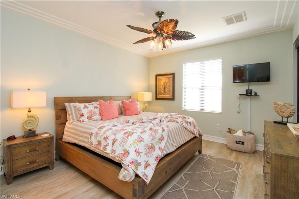 Bedroom featuring light hardwood / wood-style flooring, ornamental molding, and ceiling fan