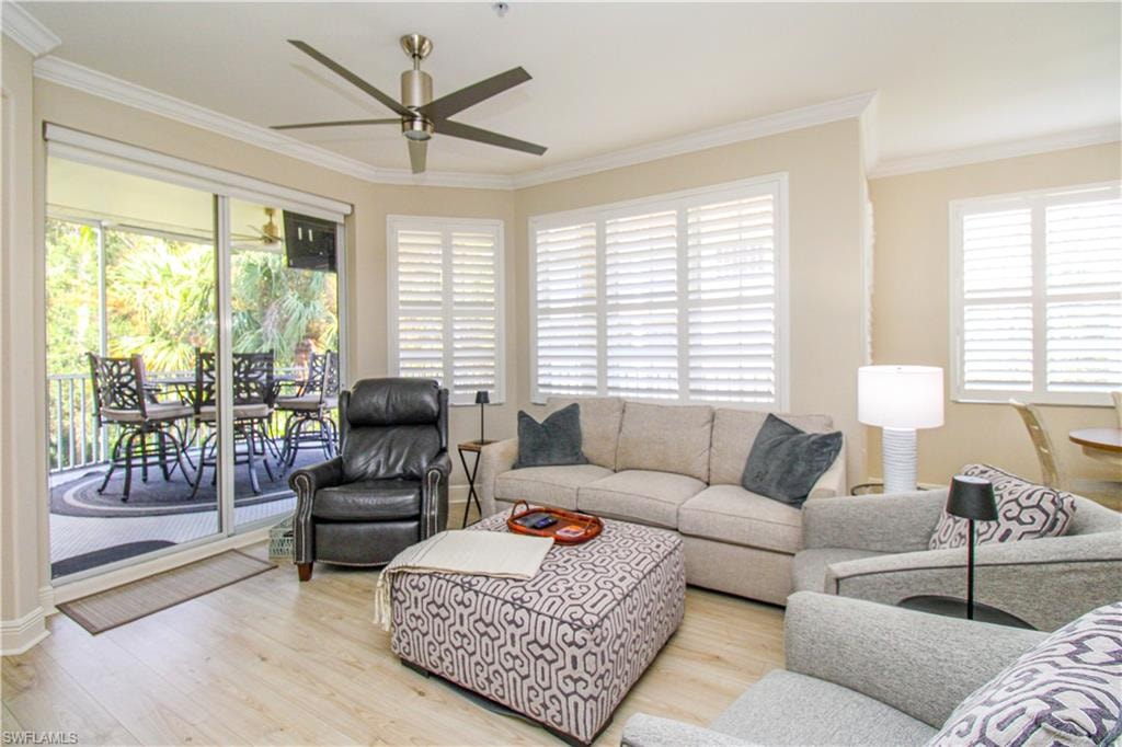 Living room with a wealth of natural light, crown molding, and light hardwood / wood-style floors