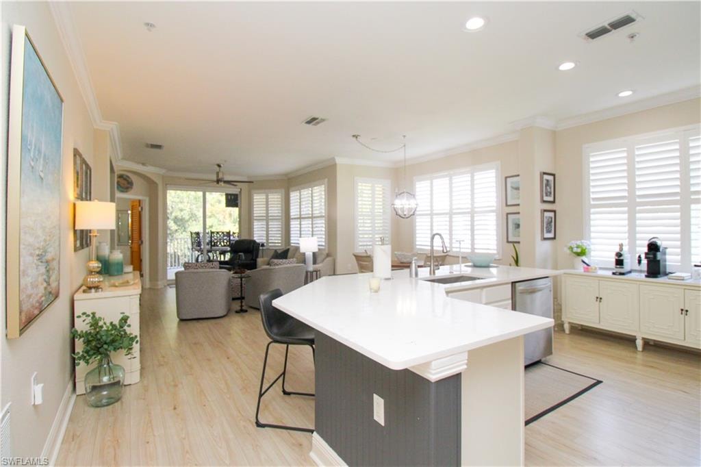 Kitchen with a breakfast bar, light hardwood / wood-style floors, crown molding, and sink