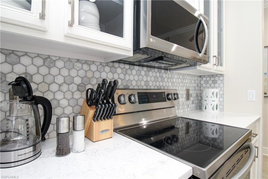 Kitchen featuring white cabinetry, stainless steel appliances, and decorative backsplash
