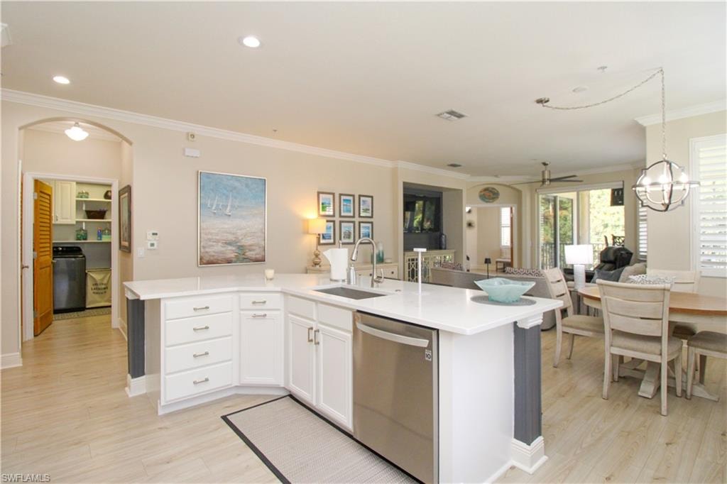 Kitchen featuring ornamental molding, sink, stainless steel dishwasher, white cabinets, and light hardwood / wood-style floors