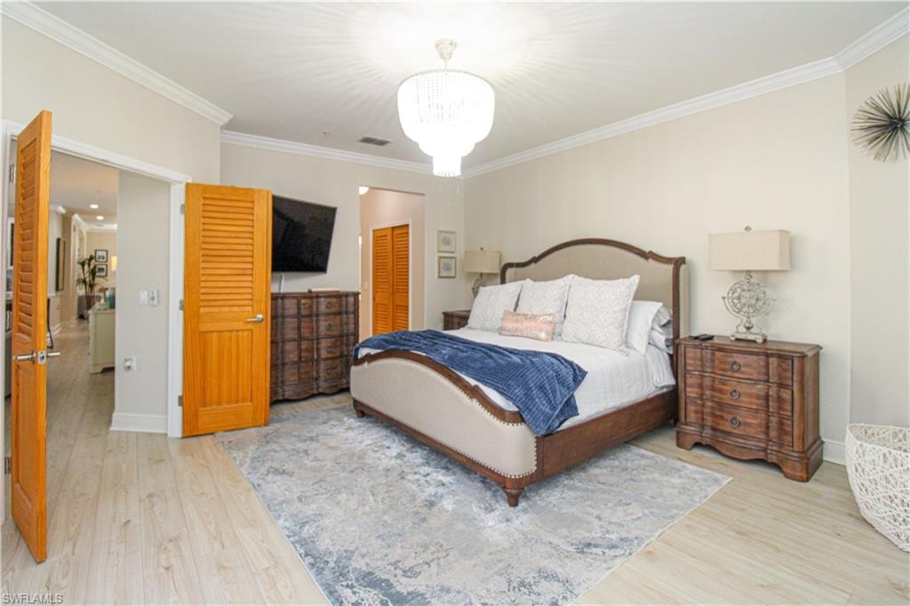 Bedroom featuring a closet, ornamental molding, light hardwood / wood-style flooring, and a chandelier