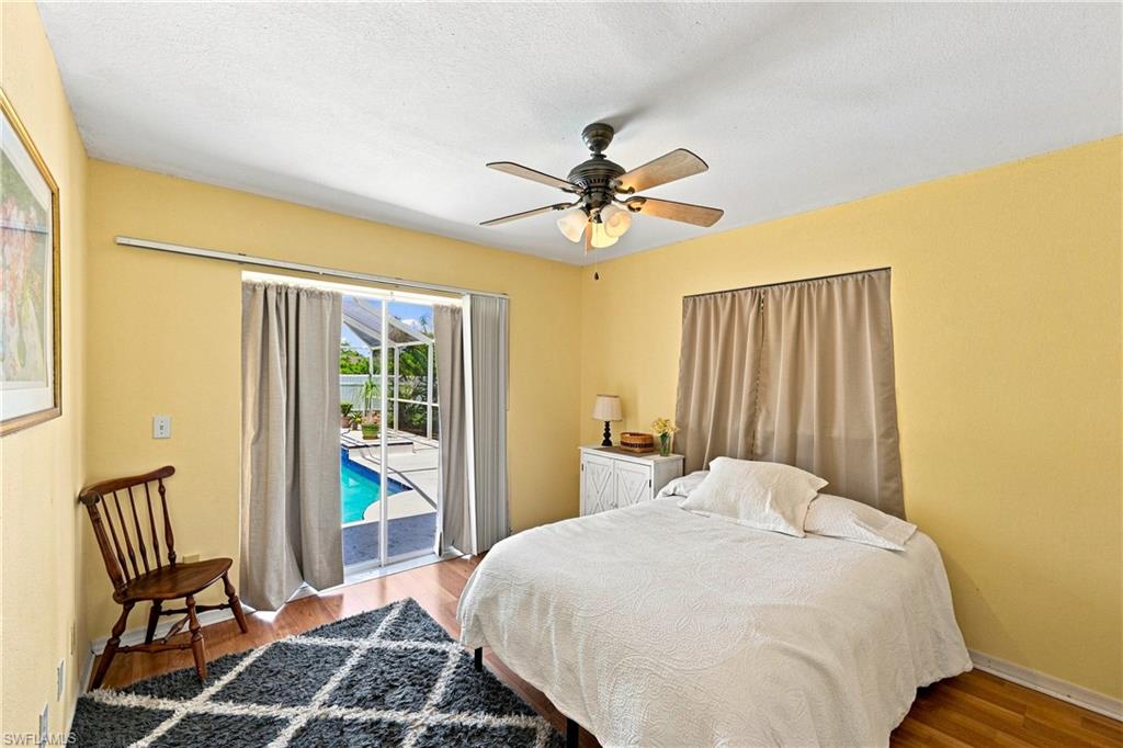 Wood-finish flooring, ceiling fan with integrated lighting, and sliding glass doors providing outdoor access