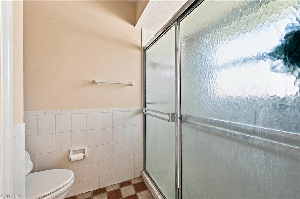 Enclosed shower with textured glass, chrome-finish framing, and tile flooring