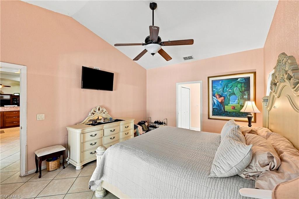 Vaulted ceiling with a ceiling fan, tile flooring, and two interior doorways
