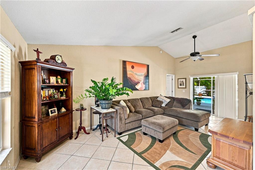 Vaulted ceilings with a ceiling fan, sliding glass doors, and tile flooring throughout