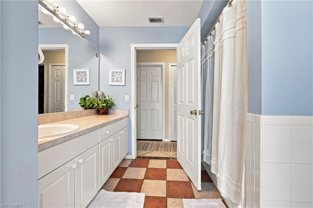 Full vanity with an integrated sink, checkerboard tile flooring, and white paneled doors