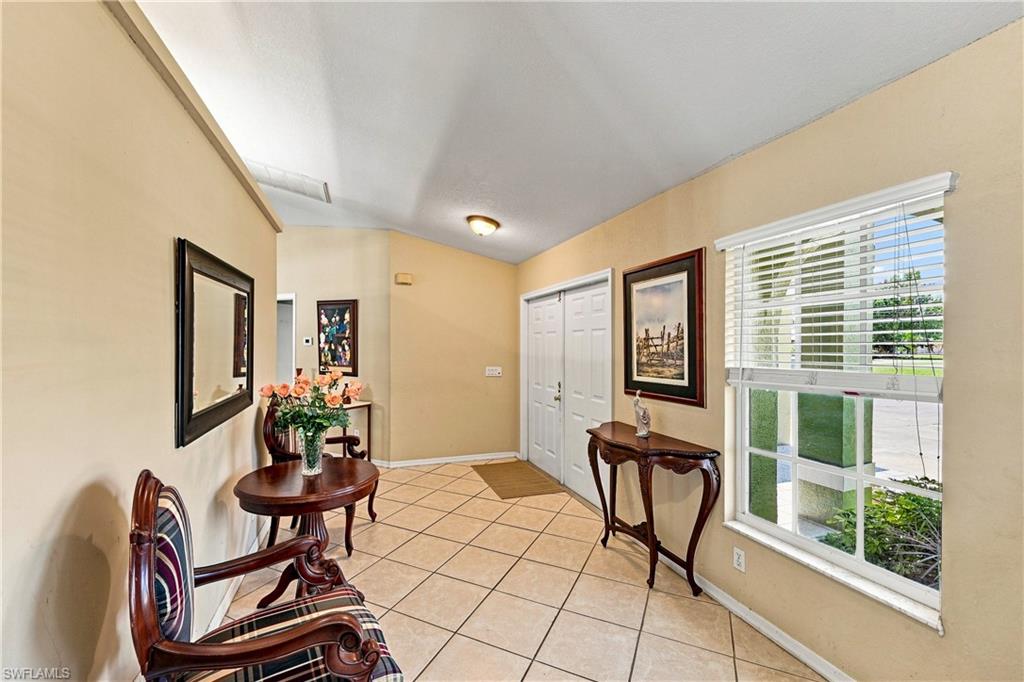 Vaulted ceiling entry with ceramic tile flooring, a large window with blinds, and bi-fold closet doors