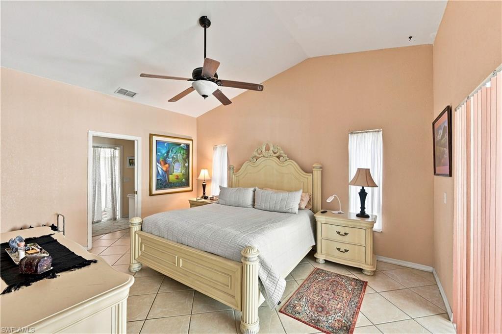 Vaulted ceiling, ceiling fan, tile flooring, and an open doorway