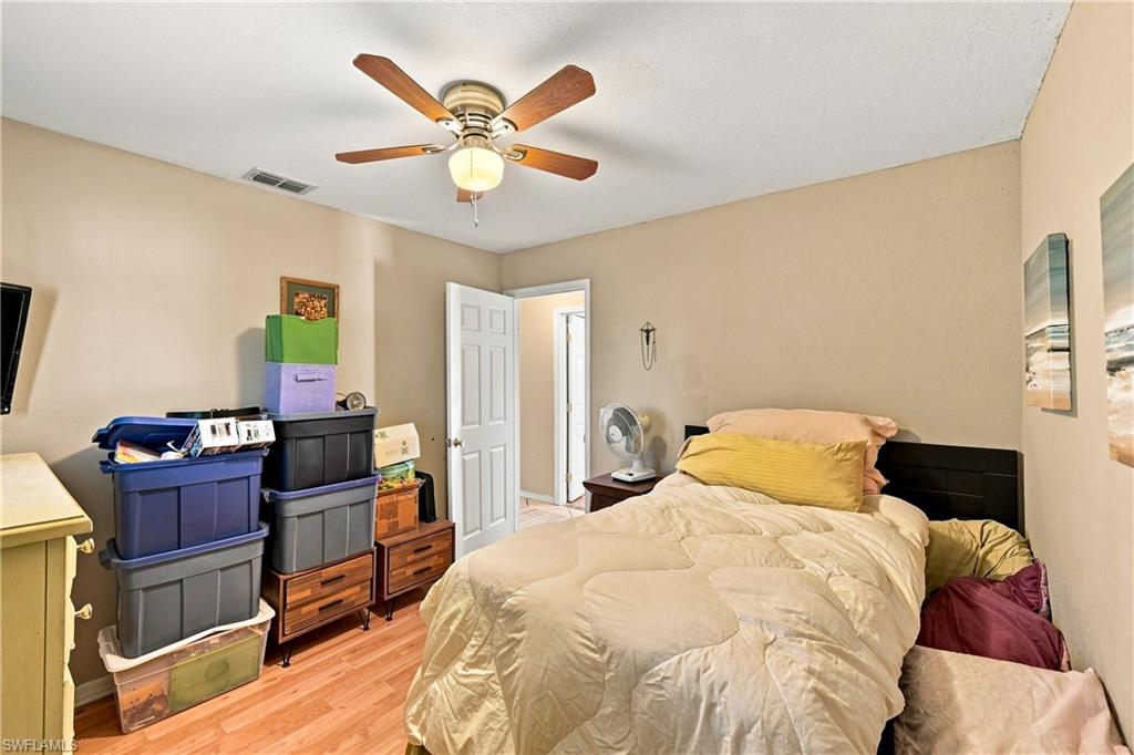 Wood-finish flooring with a ceiling fan light fixture and a solid white door