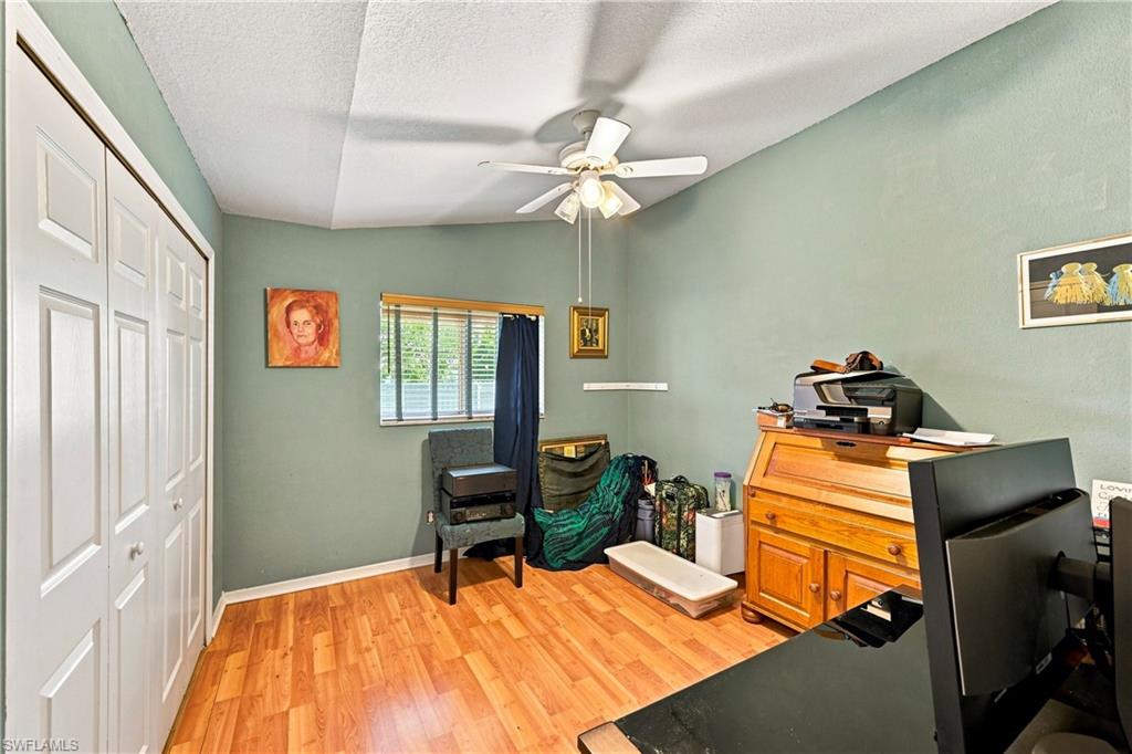 Room with wood-finish flooring, a window with horizontal blinds, and a bi-fold closet