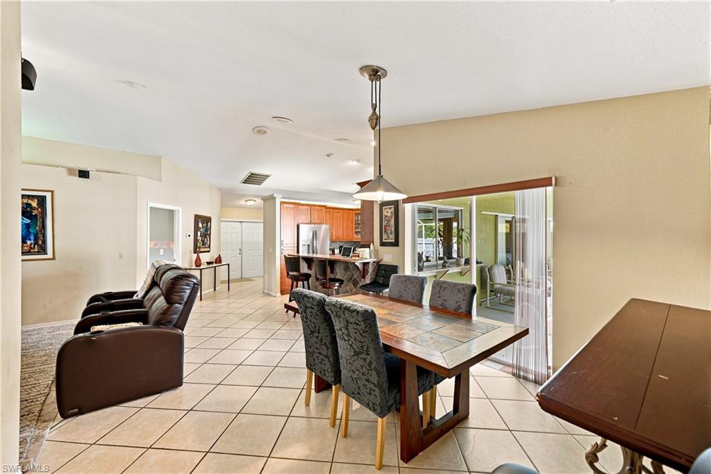Tile flooring throughout the main living areas, a dining area with a contemporary pendant light fixture, and sliding glass doors providing access to an outdoor area