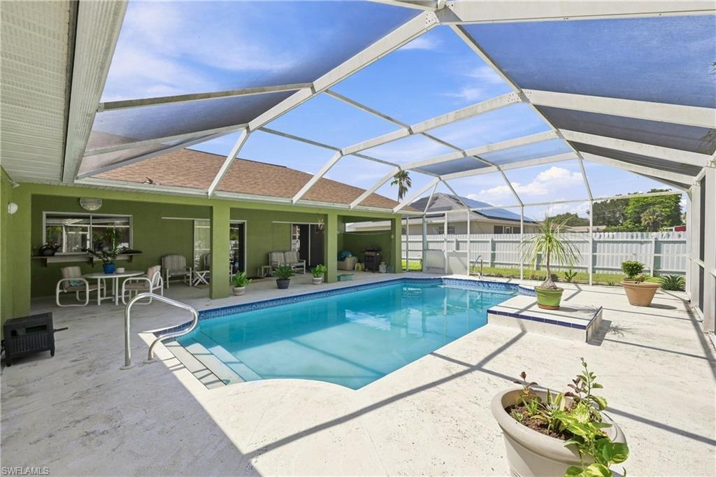 Screened swimming pool enclosure featuring a concrete patio, integrated pool steps, and a blue tiled waterline