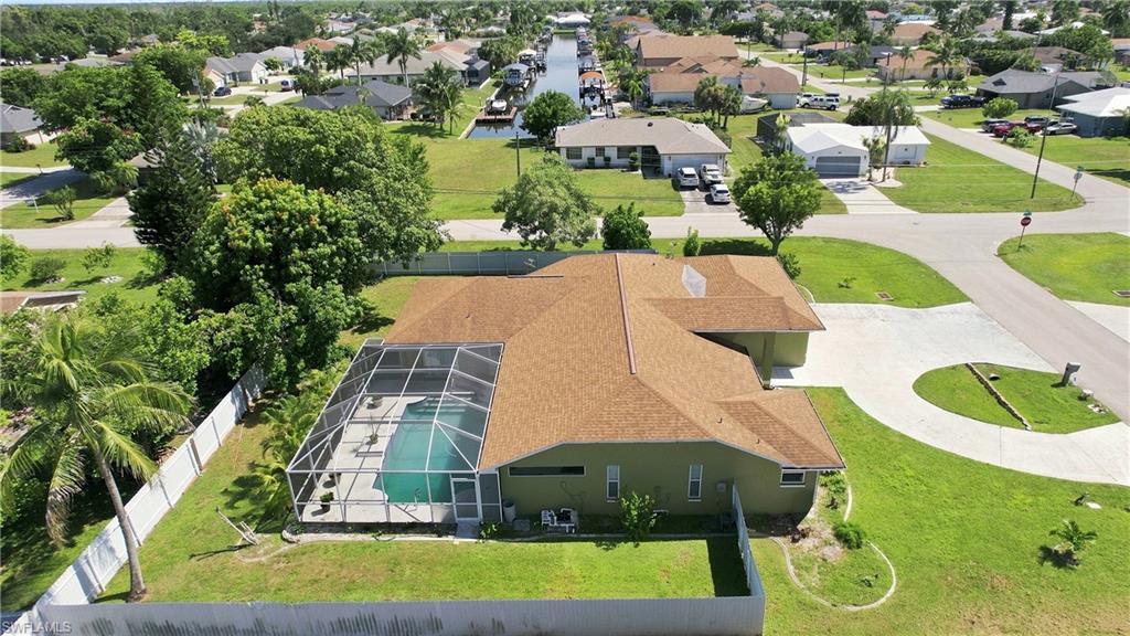 Screened swimming pool, circular driveway, mature landscaping, canal access, and a fenced yard