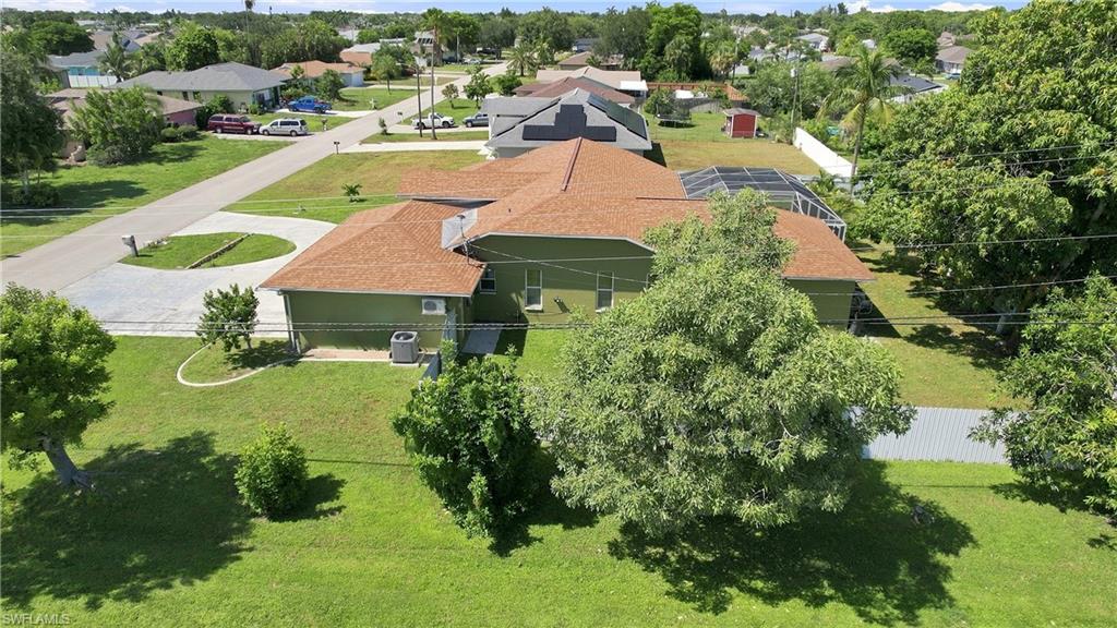 Expansive green lawn with mature trees and paved driveway