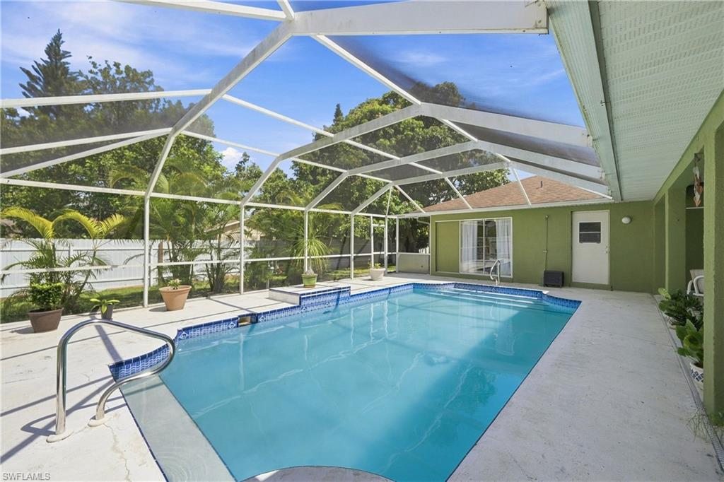 Screened-in swimming pool with concrete decking, blue tile accents, and a built-in step entry