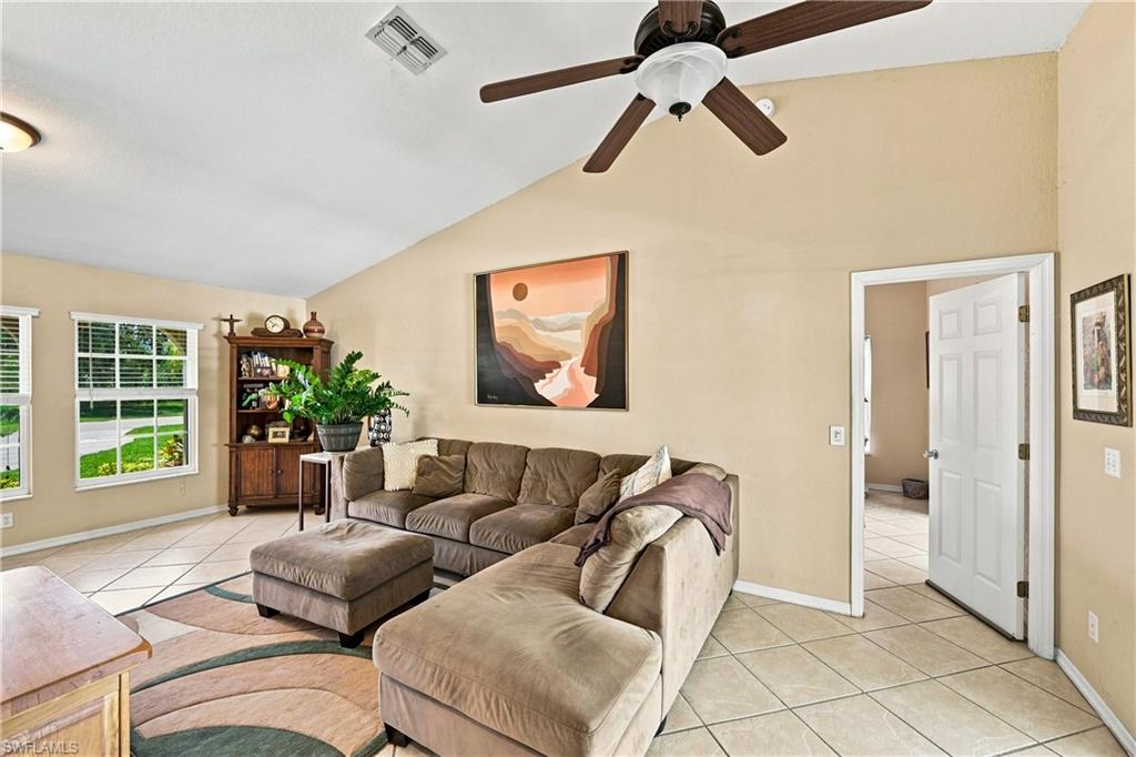 Vaulted ceiling with a ceiling fan, dual windows, and diagonally laid tile flooring