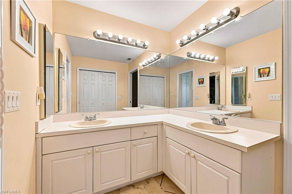 Dual vanity with integrated sinks, white cabinetry, and full-width mirrors