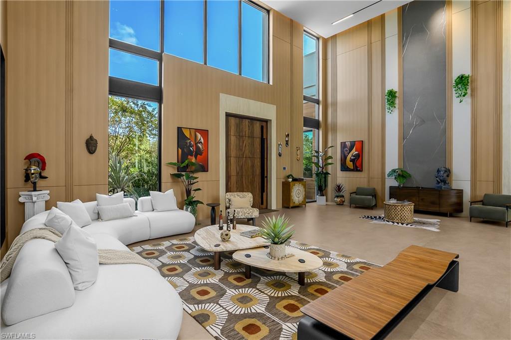 Soaring ceilings, expansive window wall, light-toned wall paneling, large-format tile flooring, and a prominent feature wall