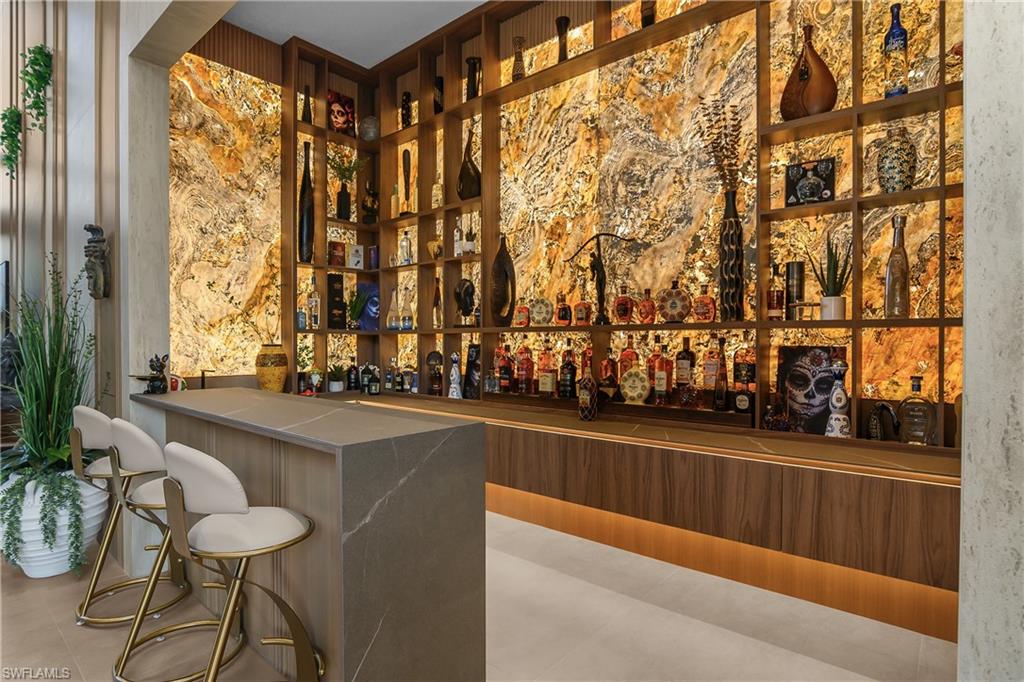Custom built-in bar with wood-finish shelving, integrated backlighting, and a stone-finish countertop