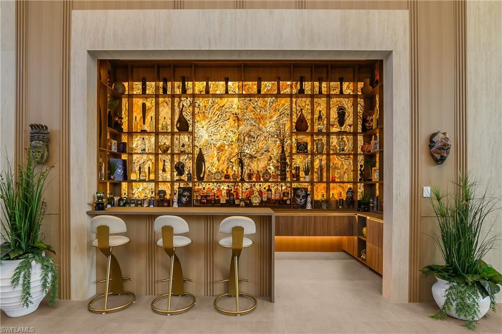 Built-in bar featuring a wood-finish countertop, back-lit shelving, and a stone accent wall