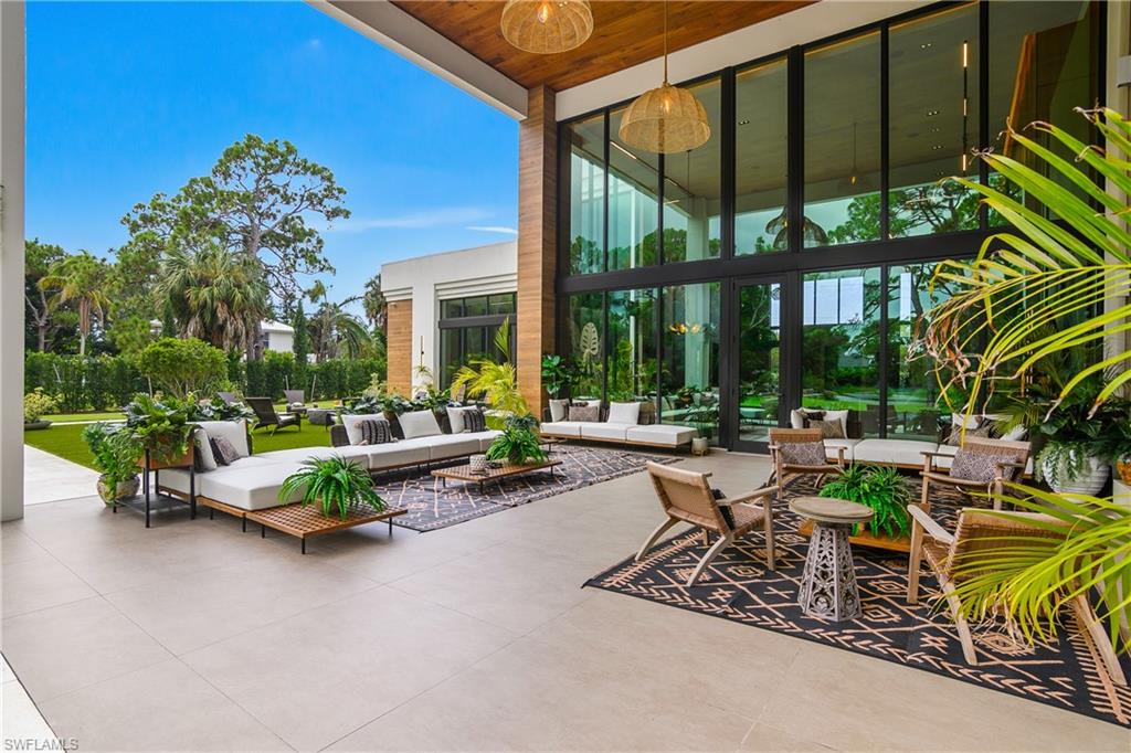 Expansive outdoor patio with large format tile flooring, a wood-finish ceiling, and full-height glass exterior walls