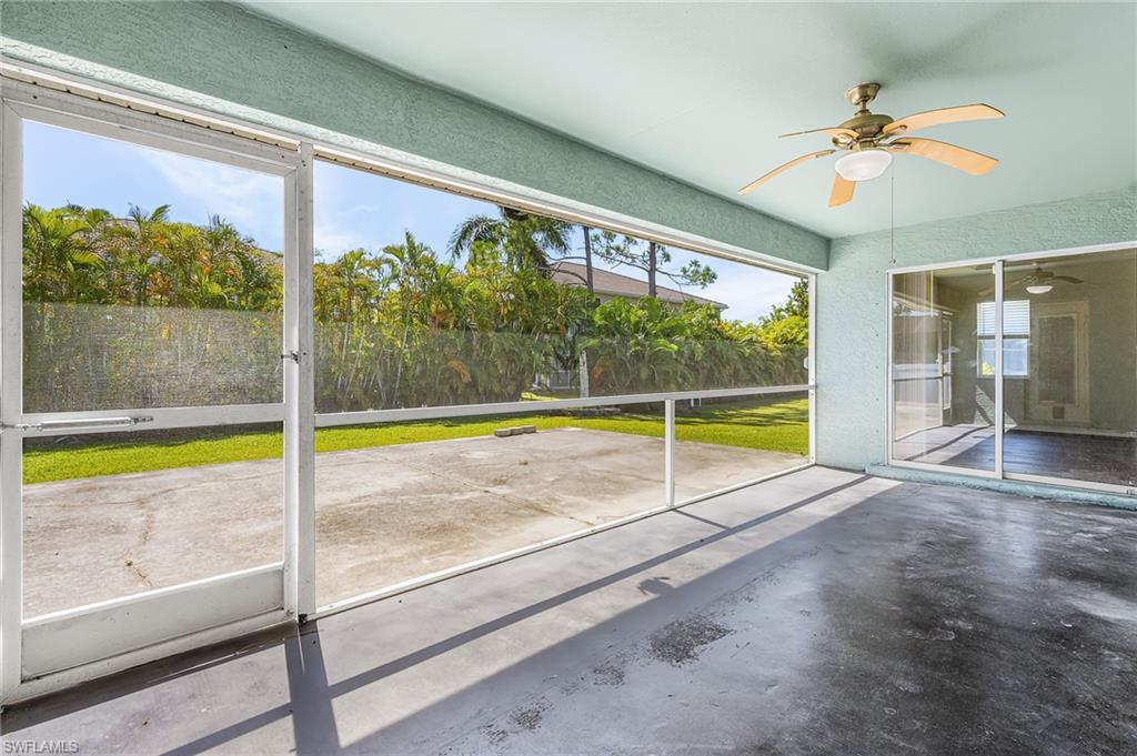 Expansive backyard featuring a lush lawn, mature perimeter landscaping, a stone-finish fire pit, and a screened patio with a concrete surface